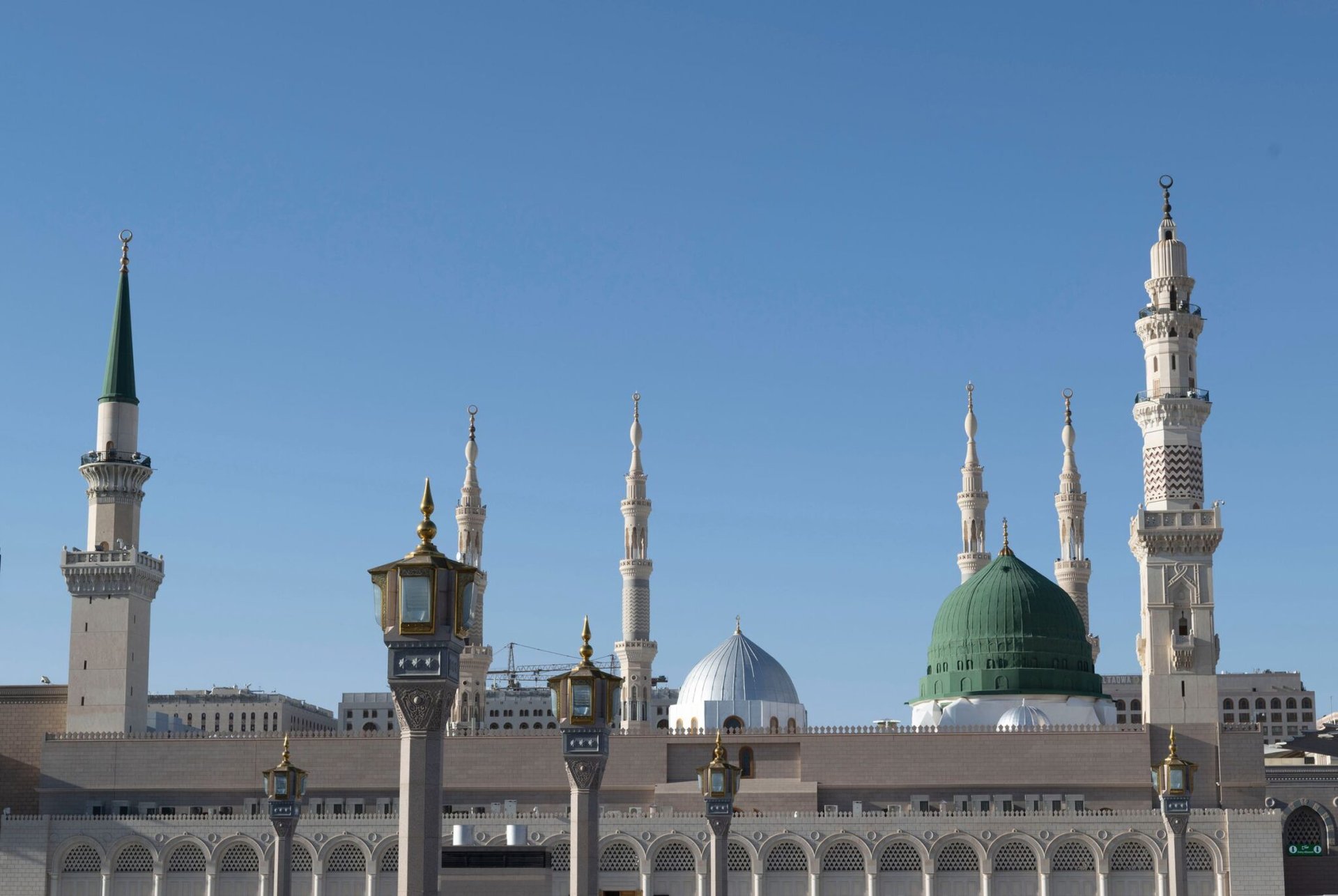 Iconic view of Al-Masjid an-Nabawi minarets against a clear blue sky in Medina, Saudi Arabia.
