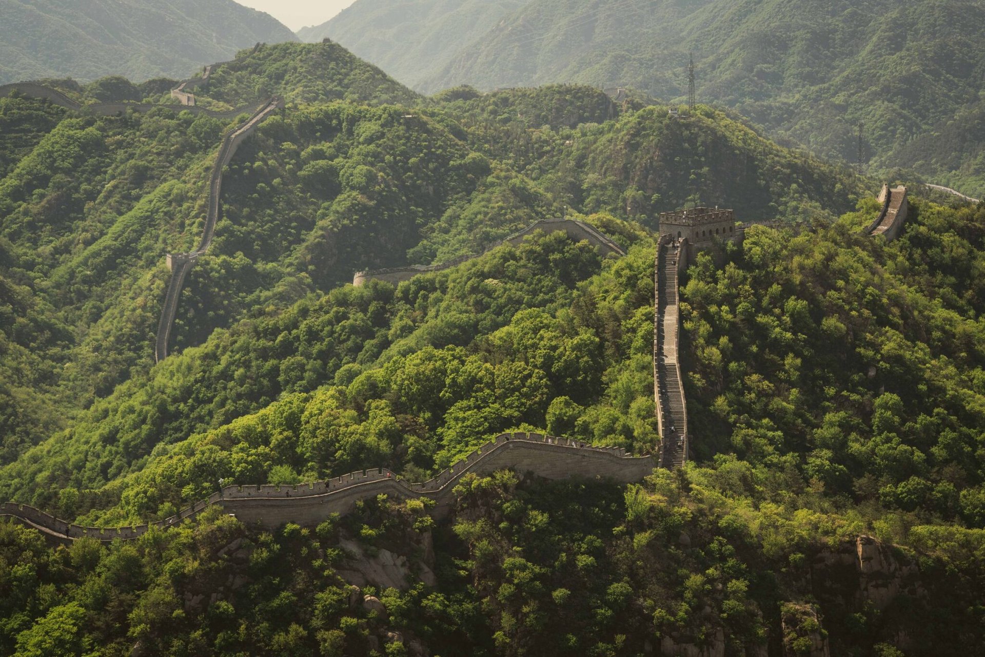 A breathtaking aerial view of the iconic Great Wall of China winding over lush green hills in Beijing.