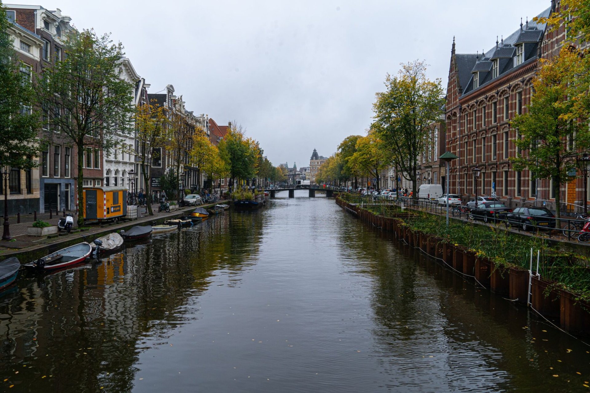 Charming view of Amsterdam's canal with classic architecture and autumn foliage.