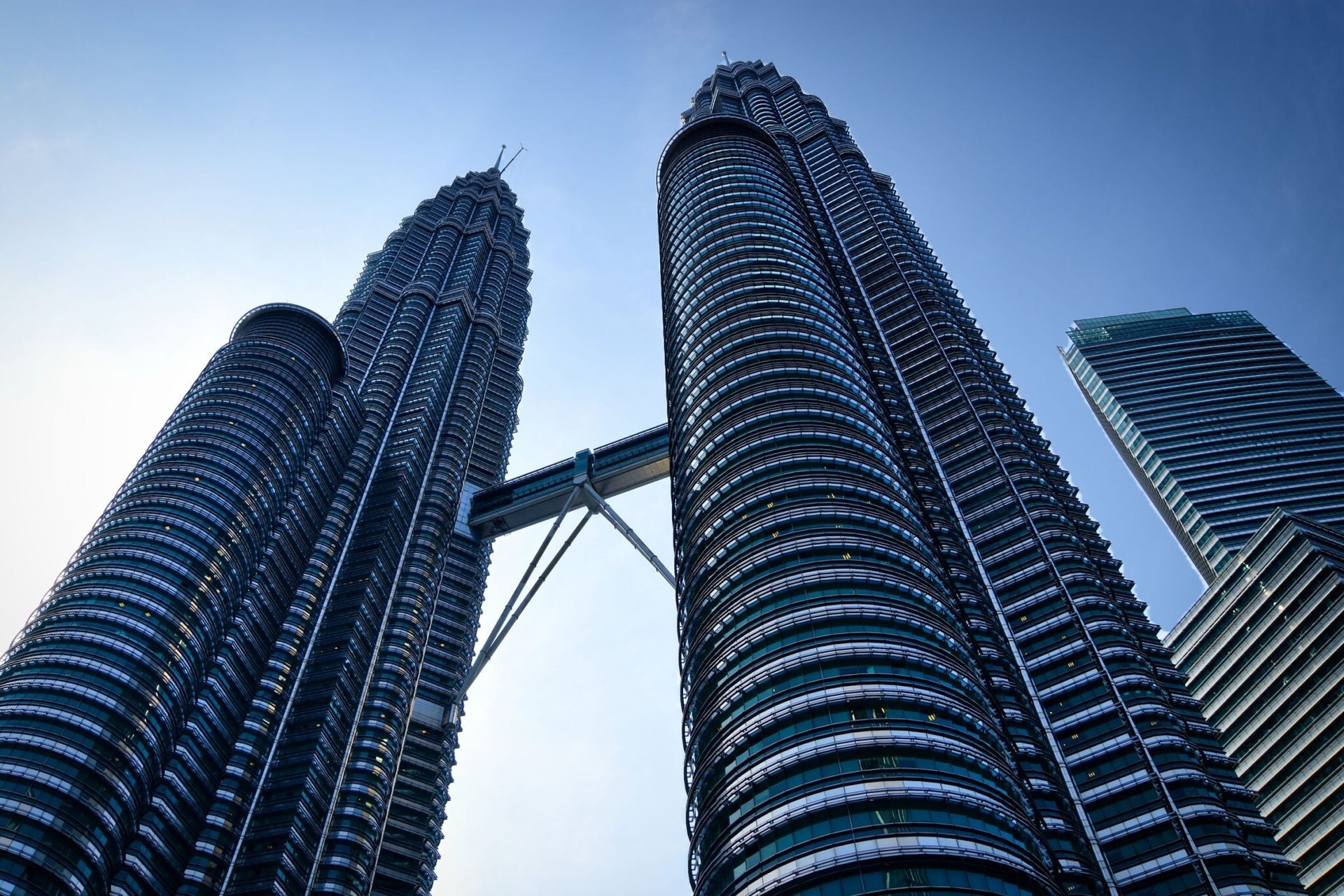 Low angle view of the iconic Petronas Twin Towers in Kuala Lumpur, Malaysia, under a clear sky.