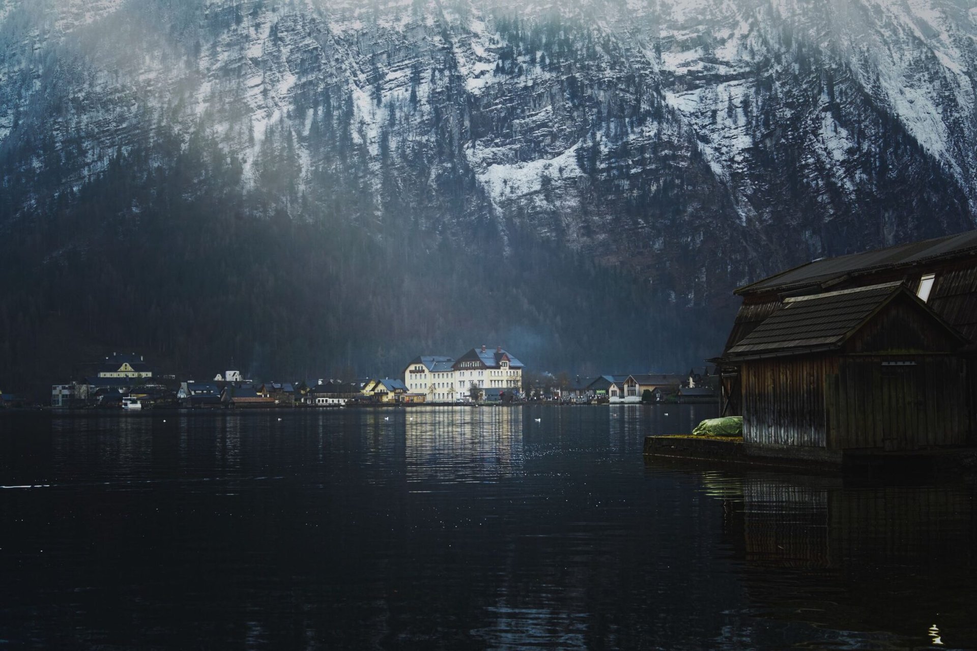 Picturesque view of Hallstatt, Austria with snowy mountains reflecting in the lake at twilight.