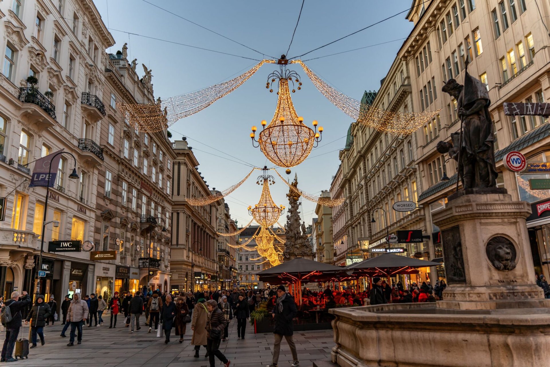 Festive lights adorn Graben street in Vienna, Austria at twilight, bustling with people.