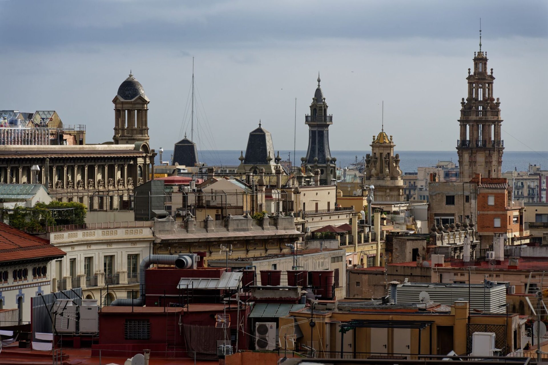 Panoramic view of historic architecture and bell towers in Barcelona, Spain with the sea in the background.