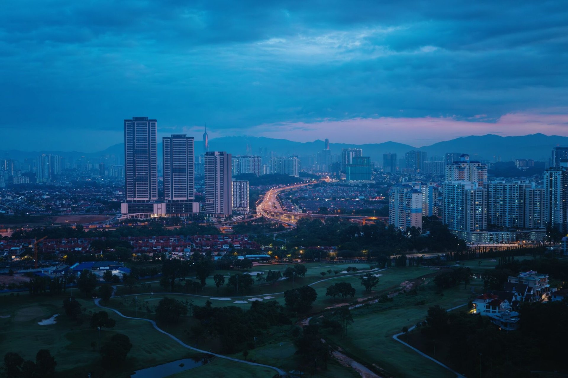 A tranquil view of Kuala Lumpur's skyline during the blue hour with soft city lights.