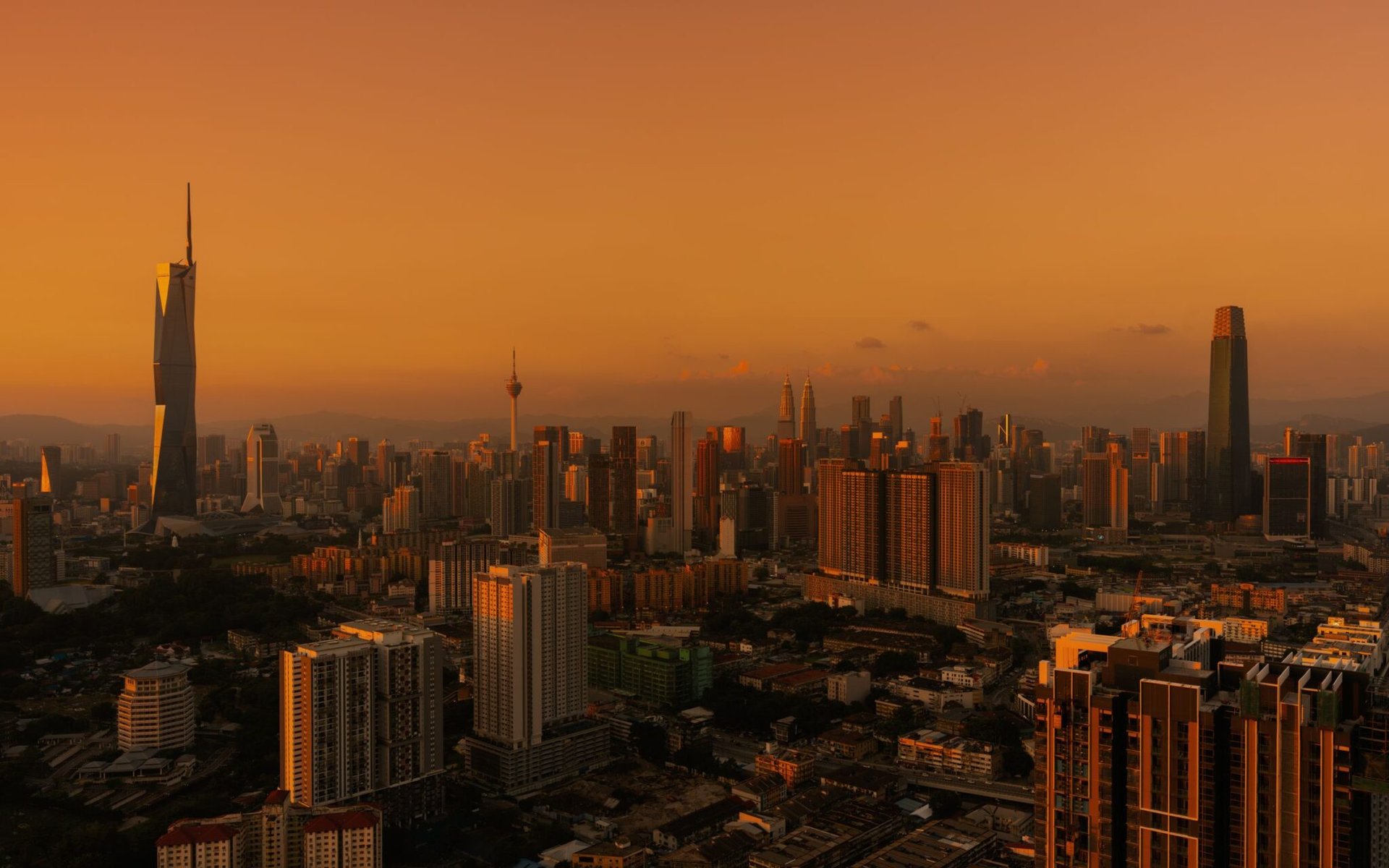 Stunning aerial view of Kuala Lumpur skyline under a warm, golden sunset.