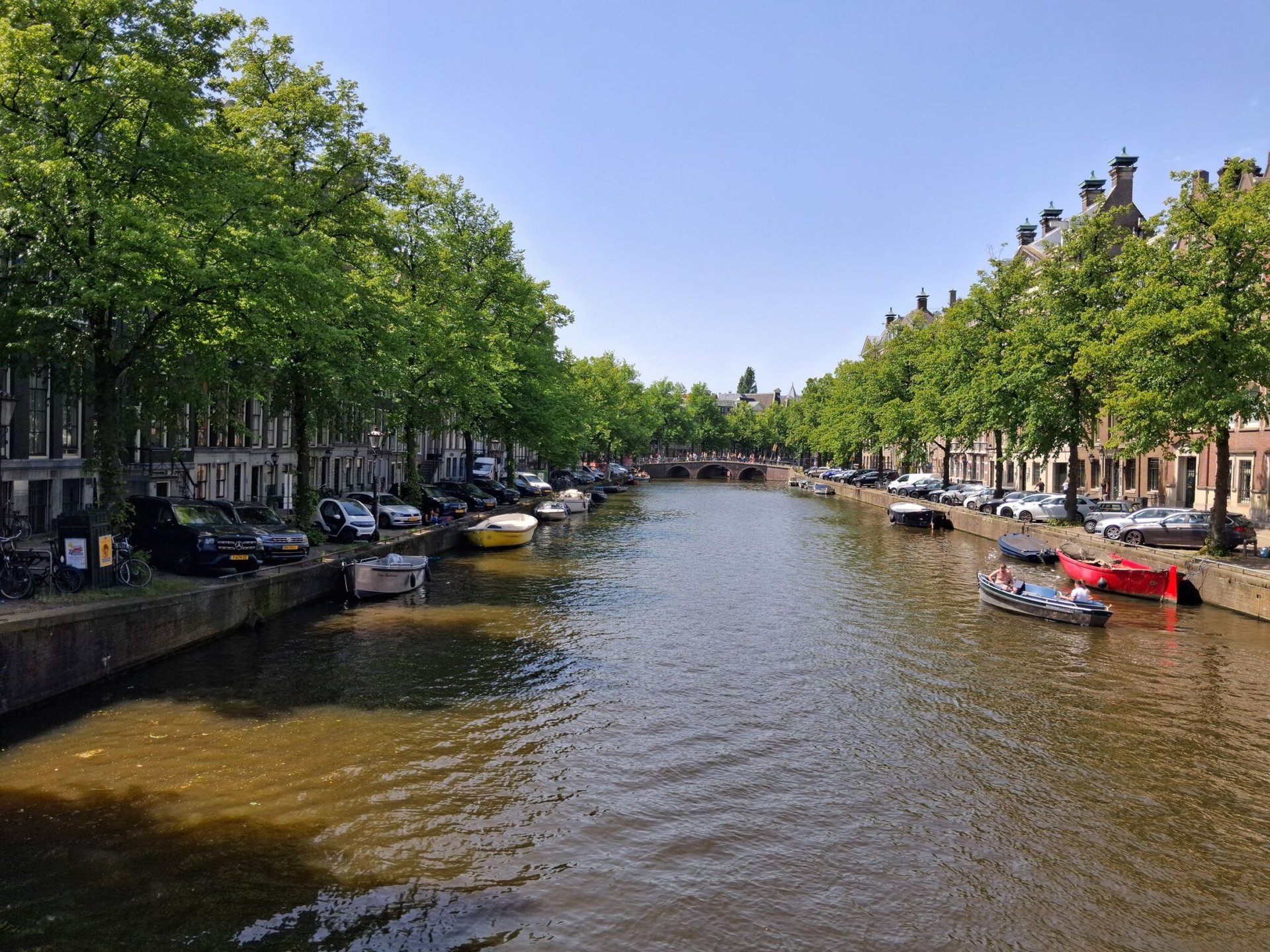 Peaceful Amsterdam canal with boats and historic architecture under a clear sky.