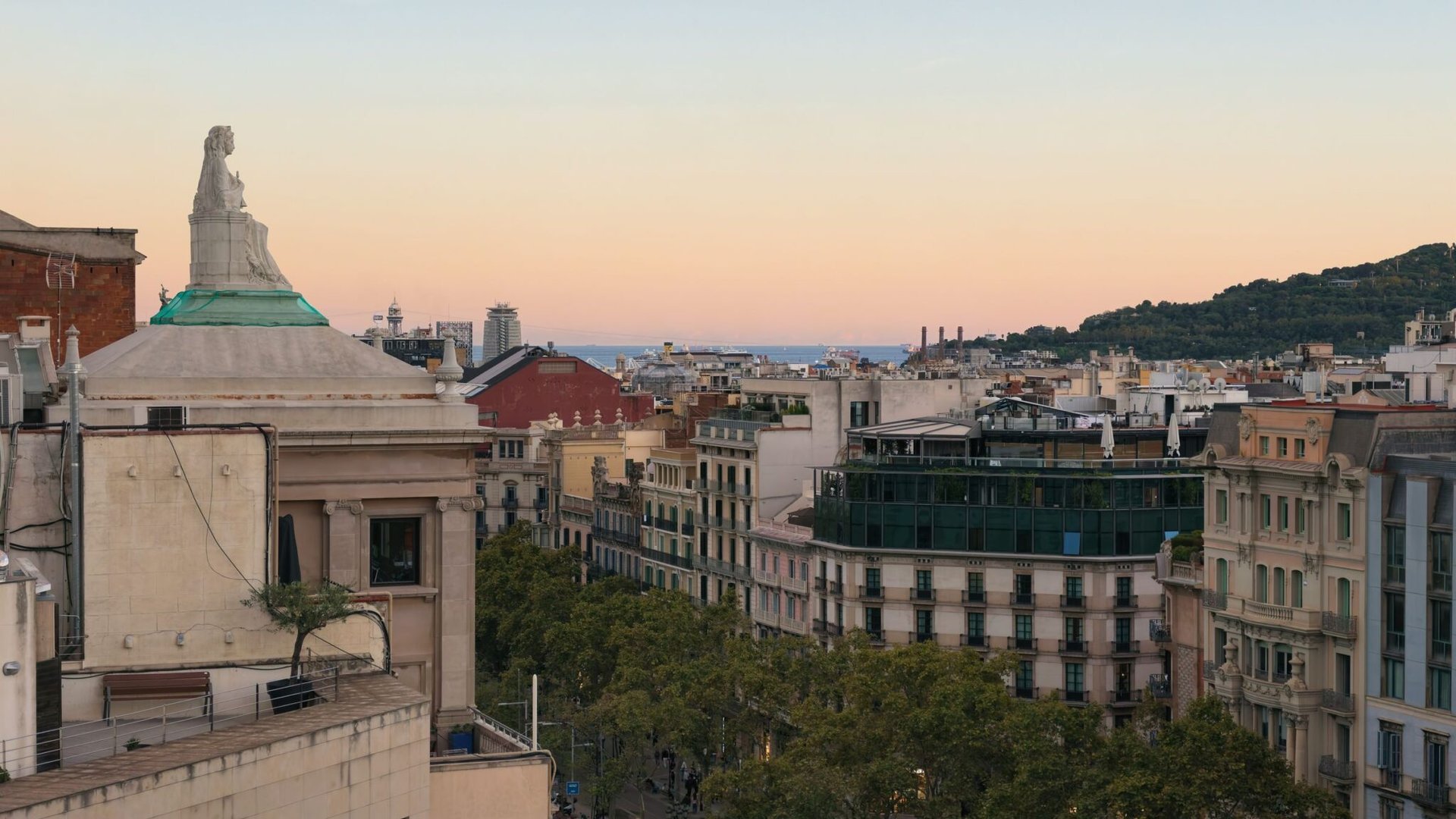 Aerial view of Barcelona's Eixample district with a pastel sky at sunset.