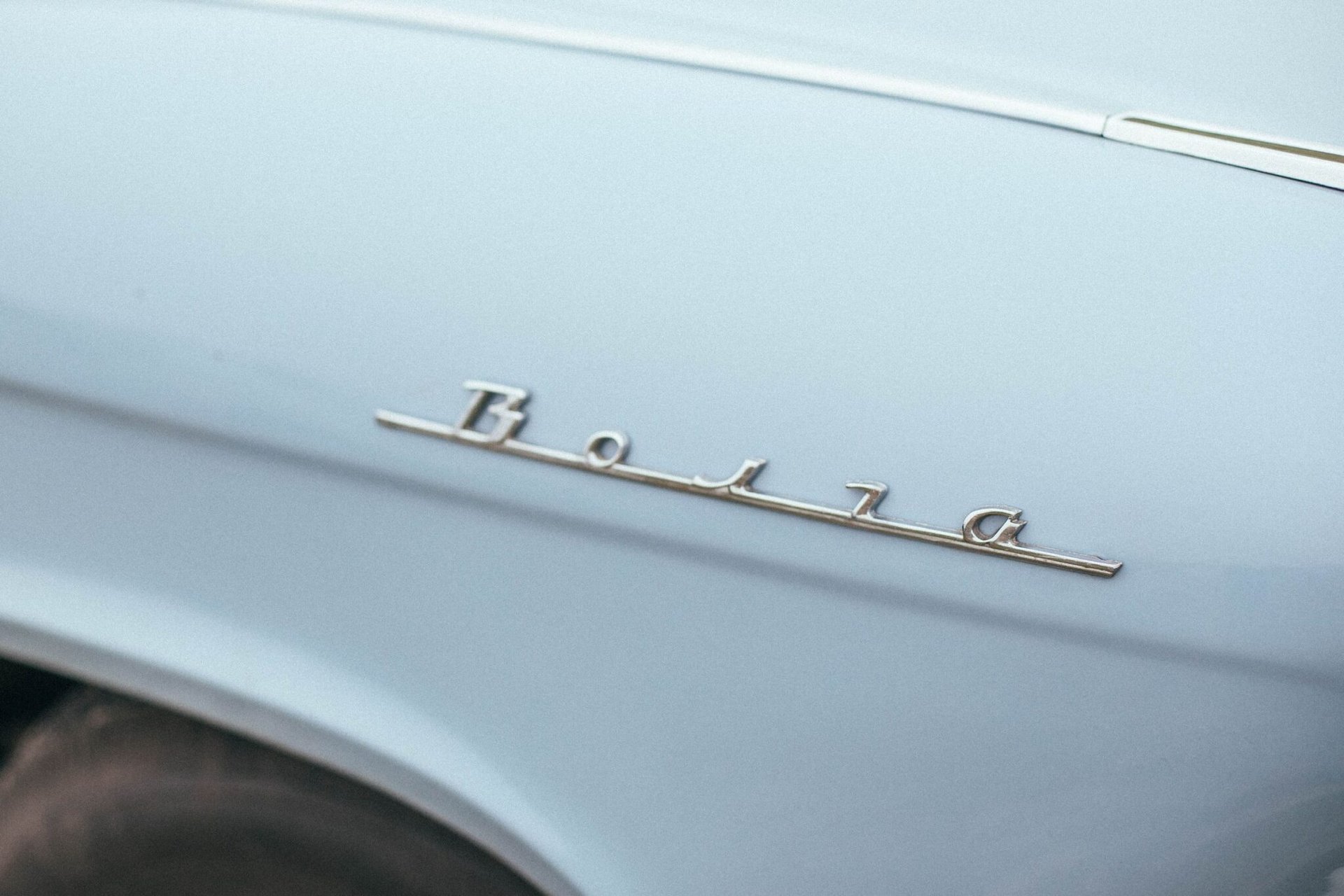Close-up of a classic blue car fender showcasing chrome 'Bora' emblem.
