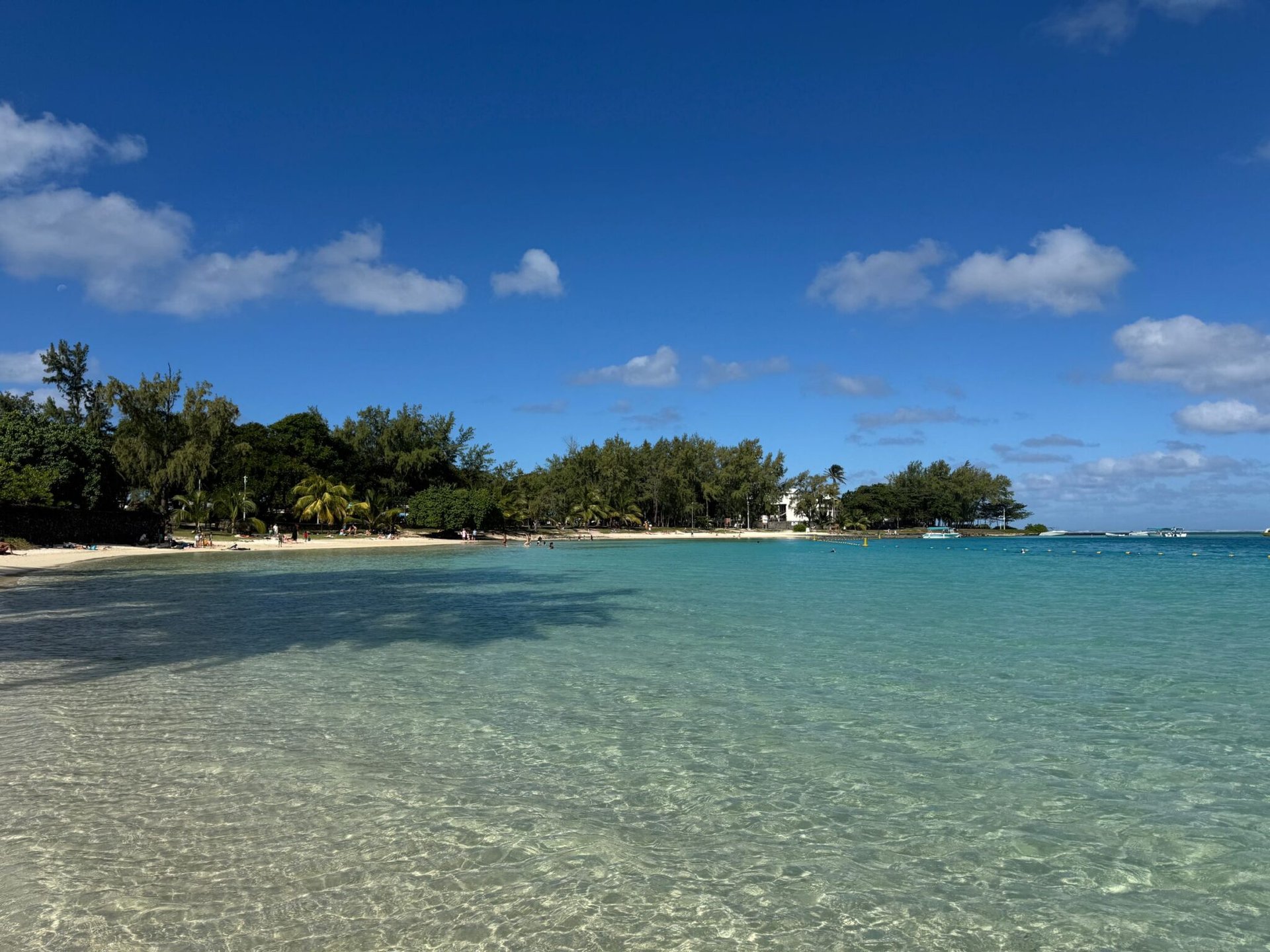 Pristine beach in Blue Bay, Mauritius with clear blue water and a sunny sky.