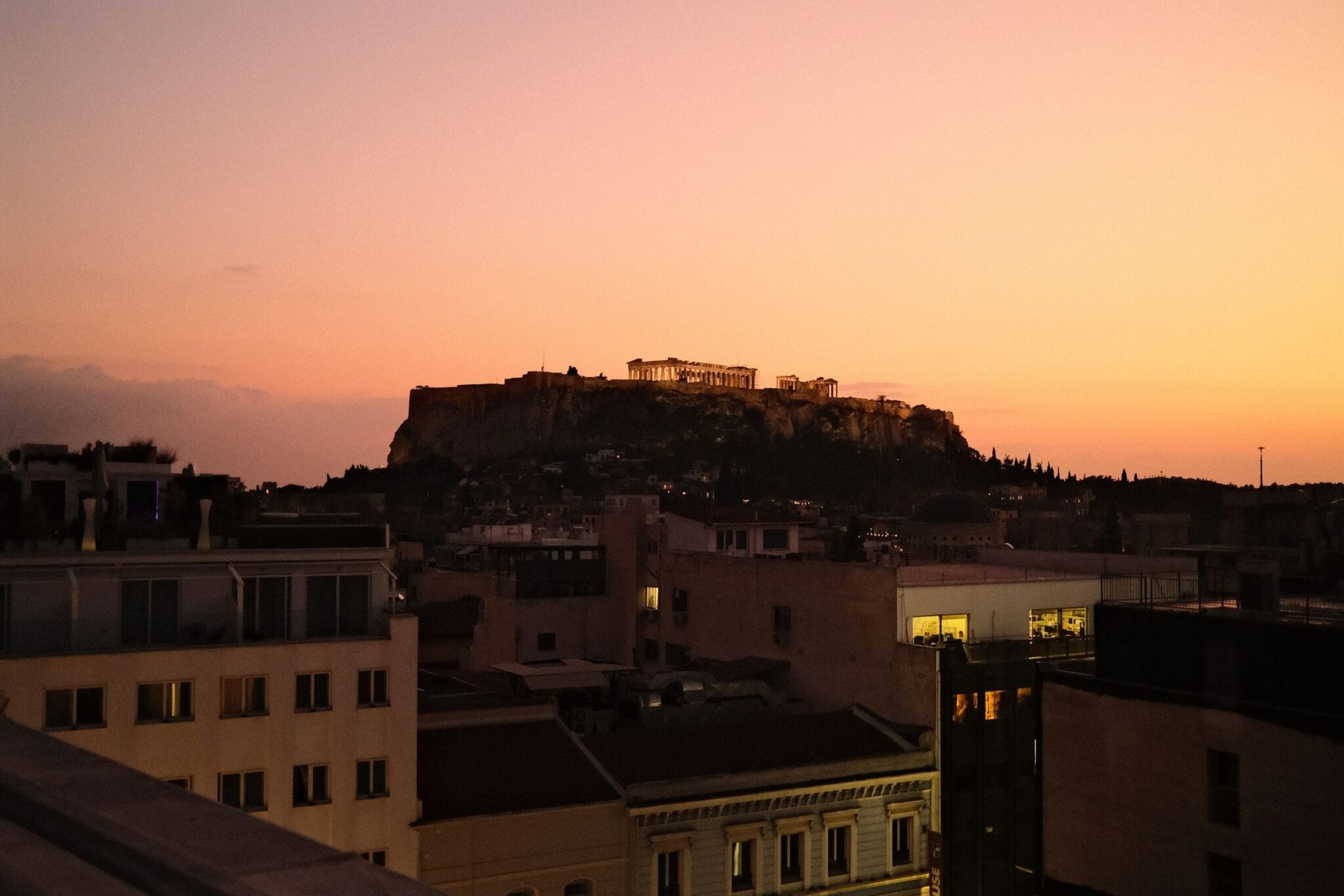 A stunning view of Athens featuring the Acropolis against a vibrant sunset sky.