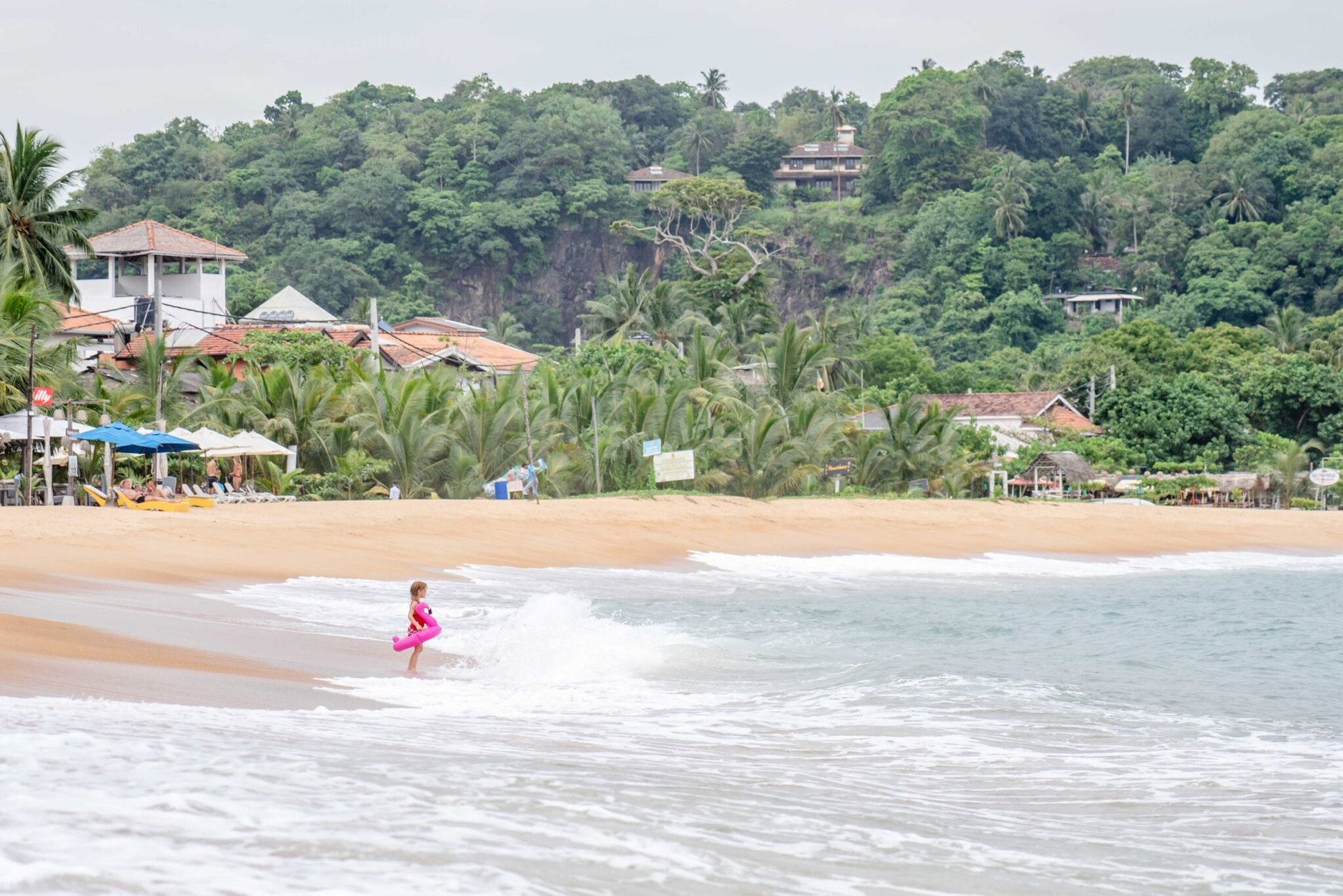 A child plays in the ocean waves at a serene tropical beach in Sri Lanka.