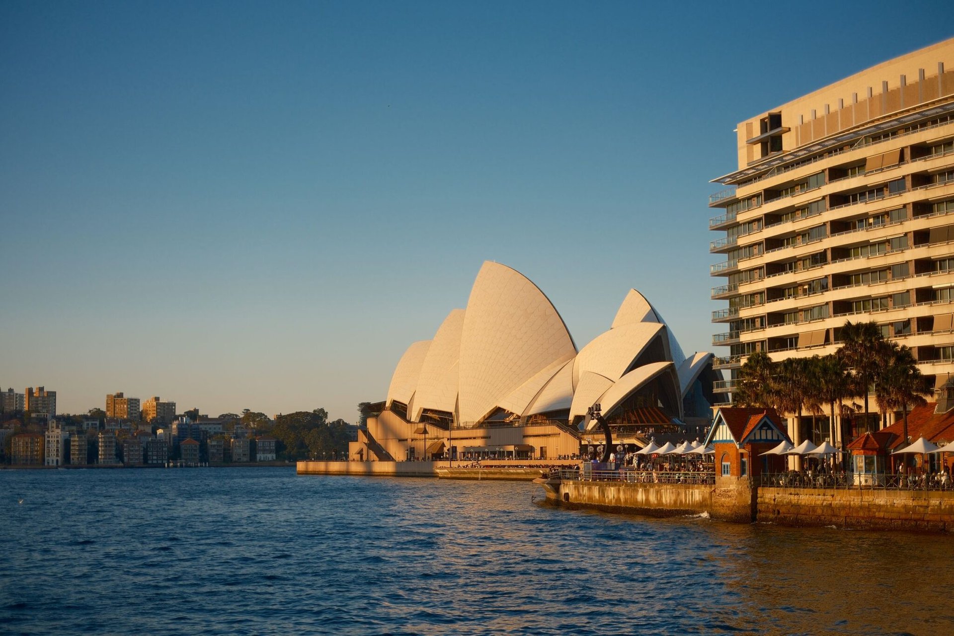 Stunning view of Sydney Opera House and waterfront during sunset, highlighting modern architecture and vibrant cityscape.