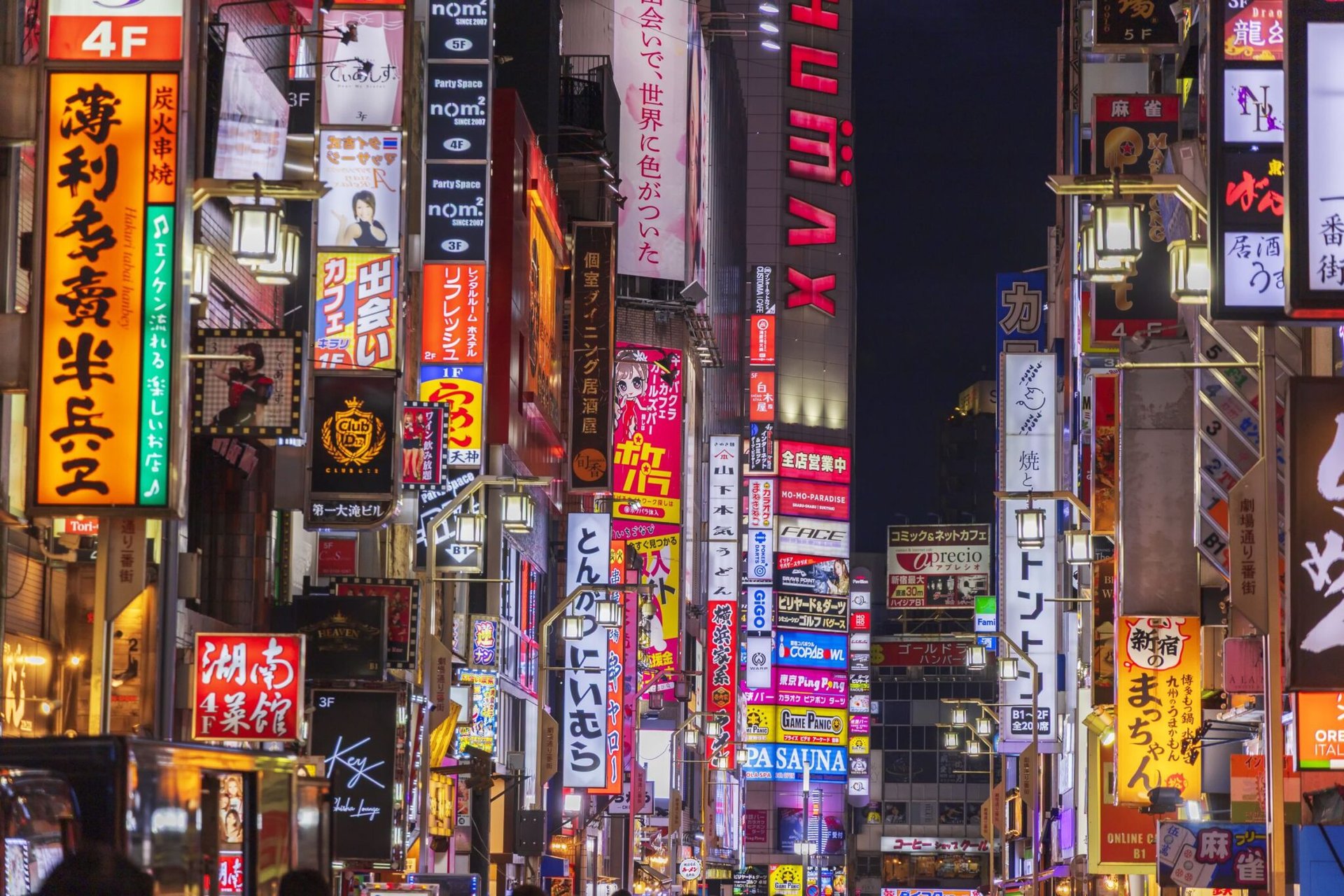 Colorful neon signs illuminate a bustling Shinjuku street in Tokyo at night, showcasing urban nightlife and culture.