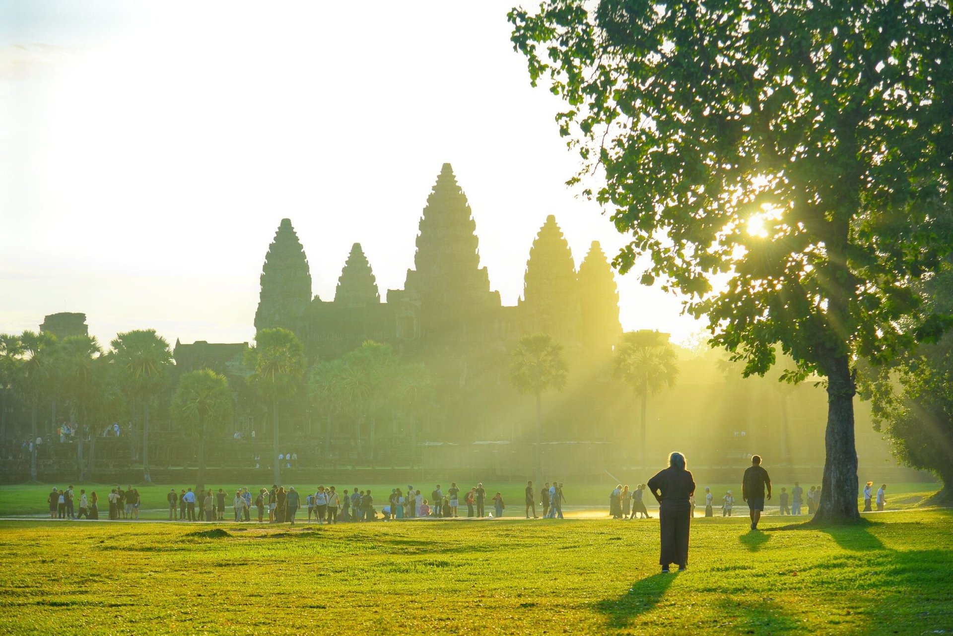 Sunrise at Angkor Wat with visitors silhouetted by the warm morning light.