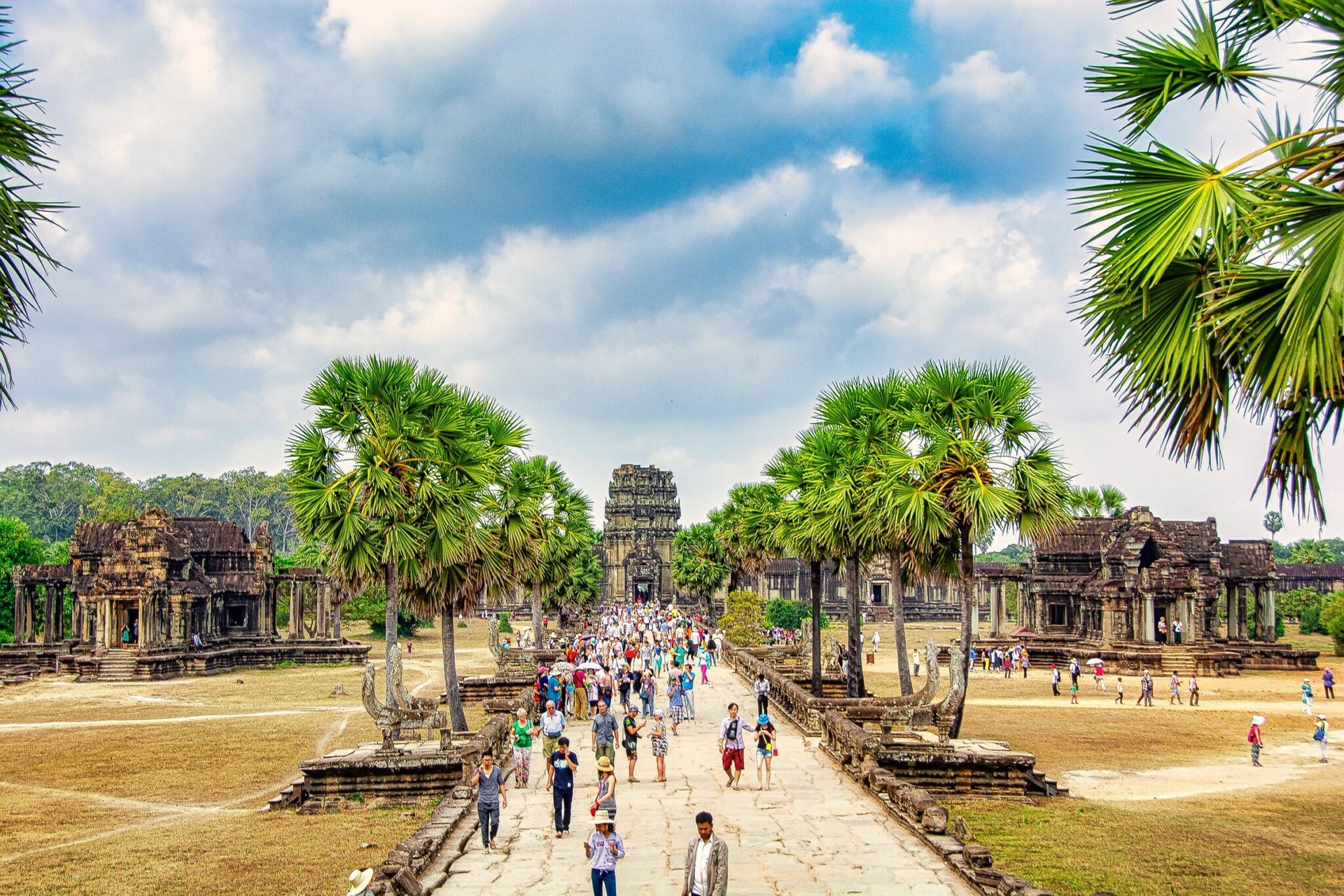 Tourists explore the iconic Angkor Wat in Siem Reap, Cambodia, under a bright sky.