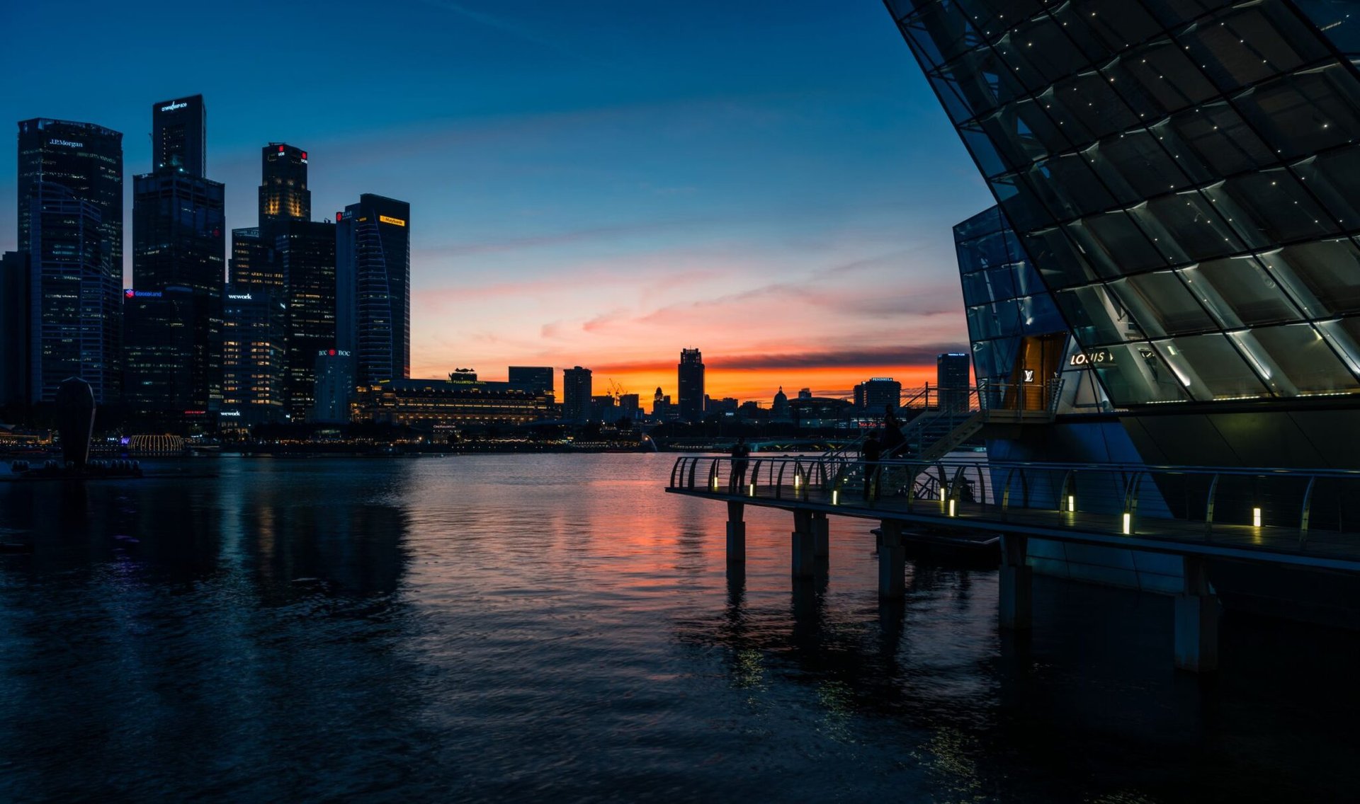 Beautiful view of Singapore skyline and Marina Bay at sunset with city lights reflecting on the water.