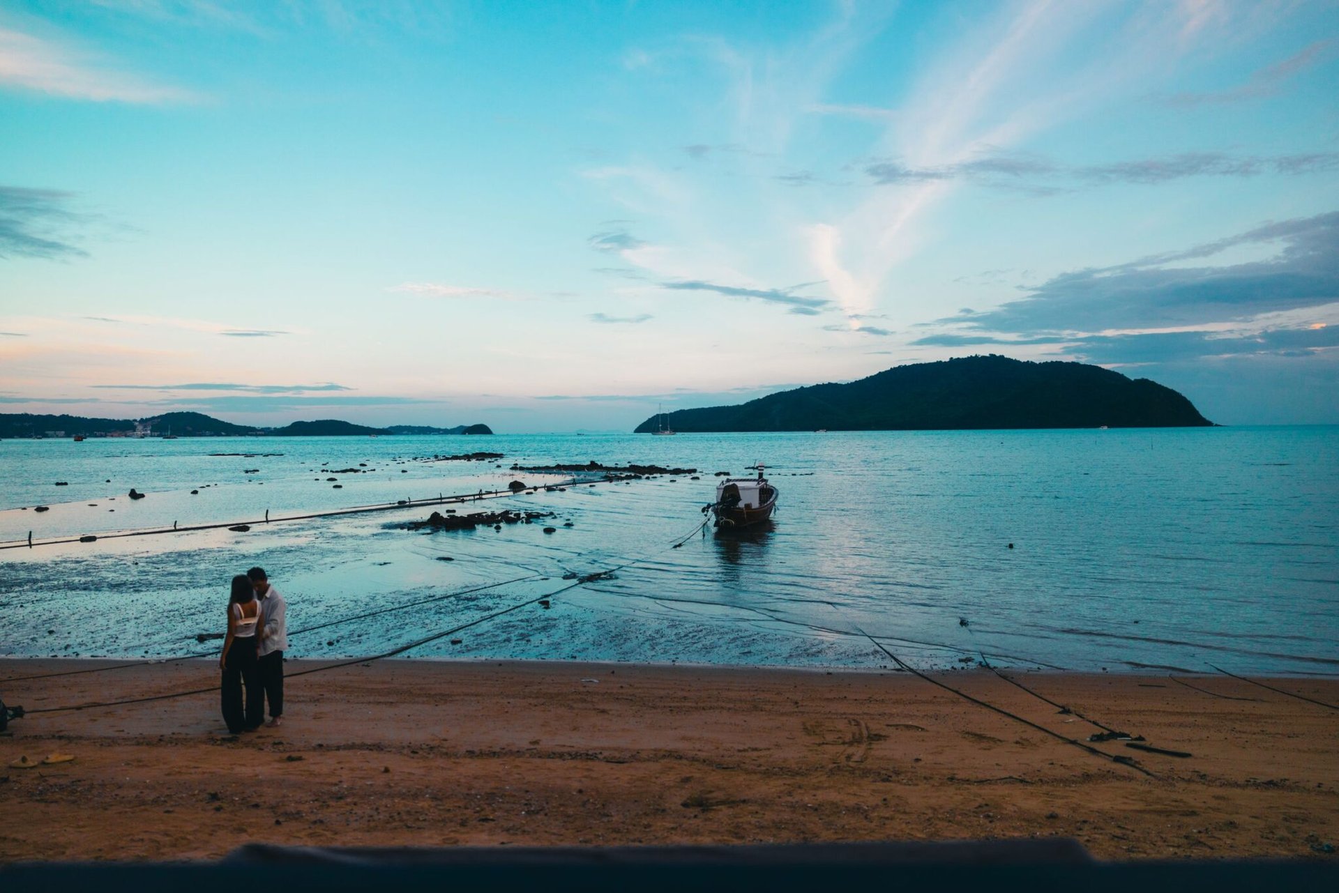 A couple shares a romantic moment on a beach in Phuket, Thailand with a serene sea backdrop.