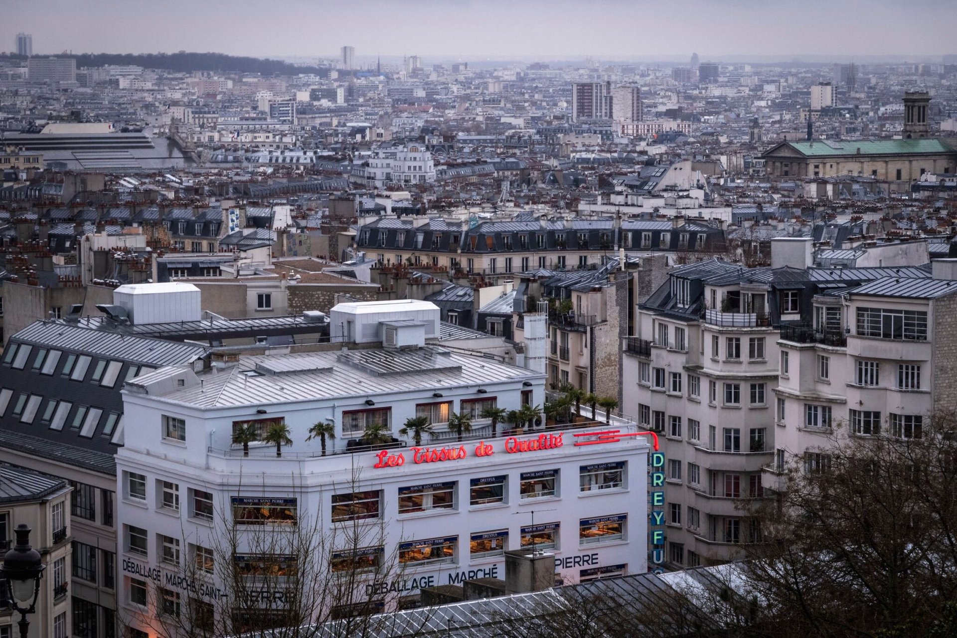 A captivating view of Paris rooftops showcasing dense urban architecture during a cloudy day.