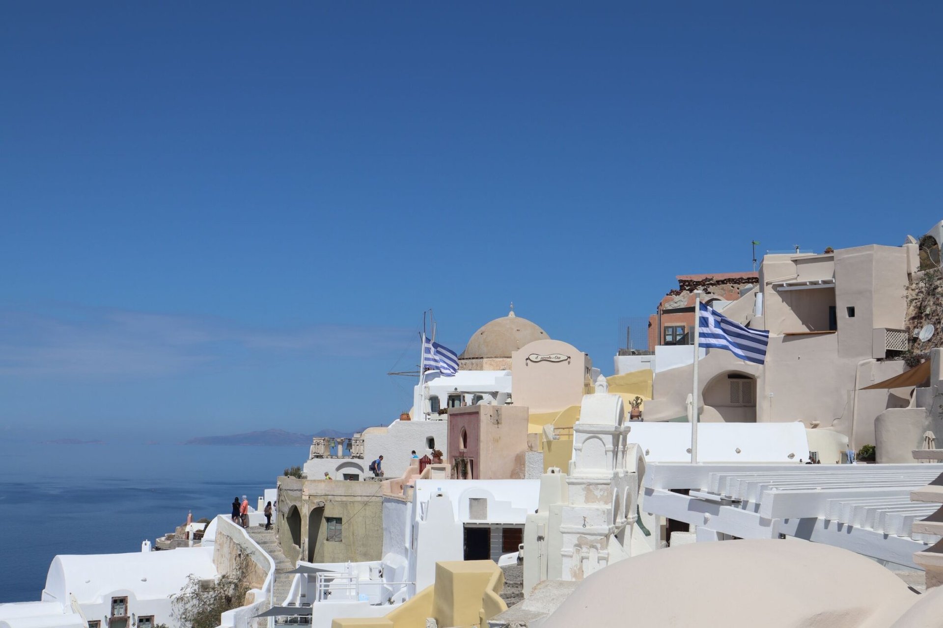 Breathtaking Santorini village of Oia with iconic Greek architecture and flags.