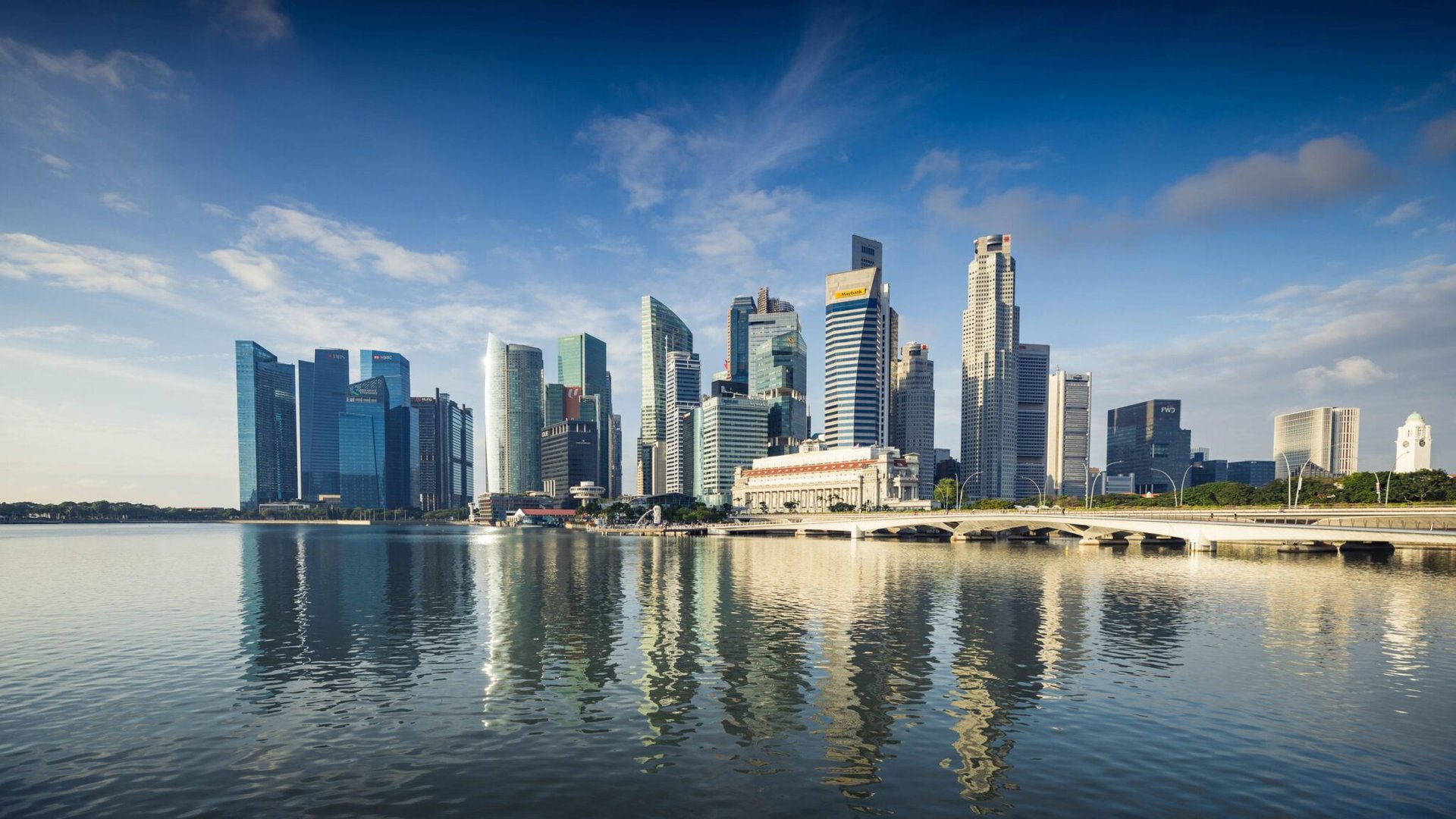 Capture of Singapore's modern skyline featuring reflective skyscrapers against a blue sky.