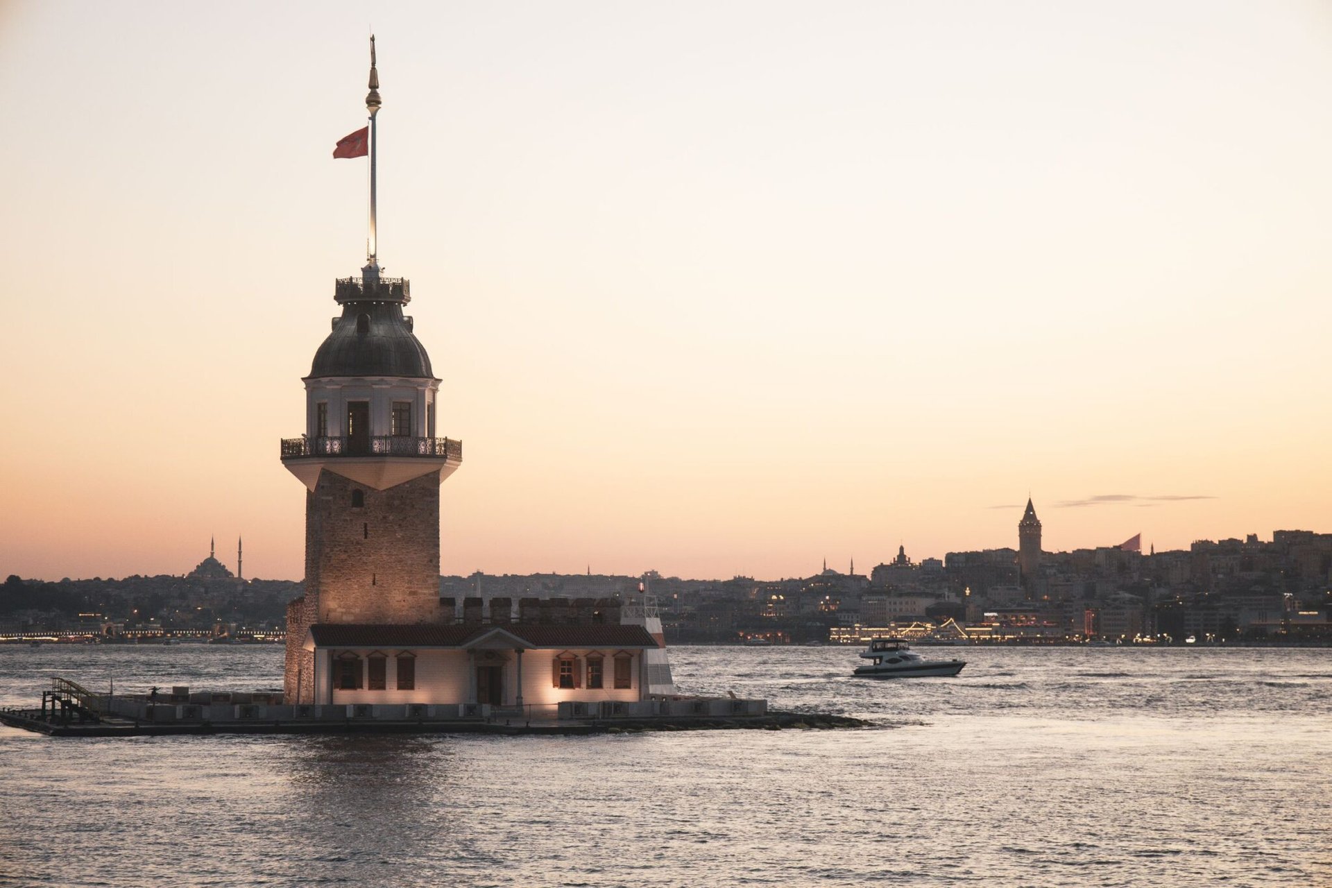 The scenic view of Maiden's Tower during sunset in Istanbul, Türkiye, with cityscape and boat.