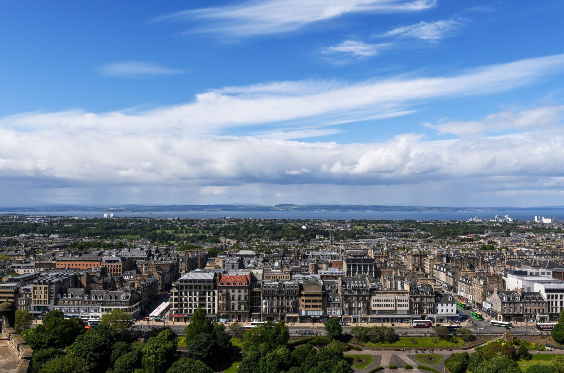 A panoramic cityscape of Edinburgh, Scotland showcasing historic architecture under a clear blue sky.