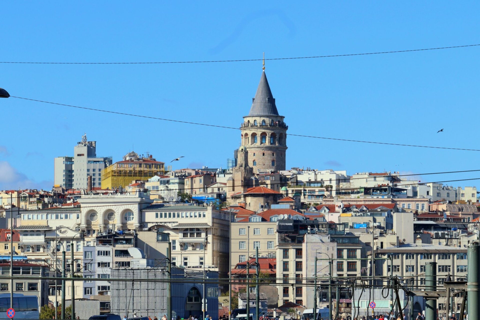 A panoramic view of Galata Tower surrounded by historic buildings in Istanbul, Turkey under a clear blue sky.